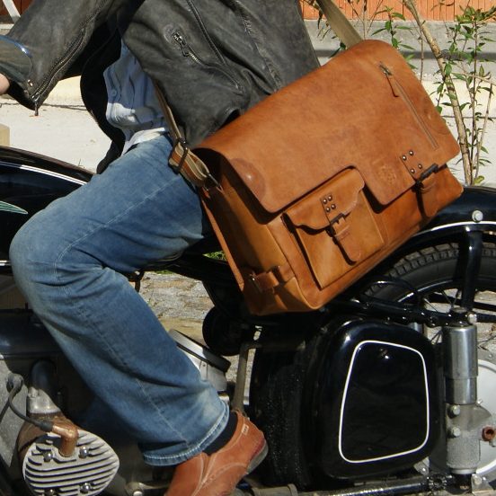 Ledertaschen Freiherr von Maltzahn Person mit brauner Umhängetasche aus Leder sitzt auf einem Motorrad.