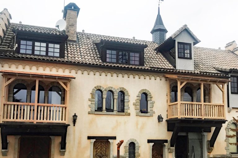 Ferienwohnungen im Rittergut Leppersdorf Historisches Gebäude mit Holzveranden und spitzen Türmen.