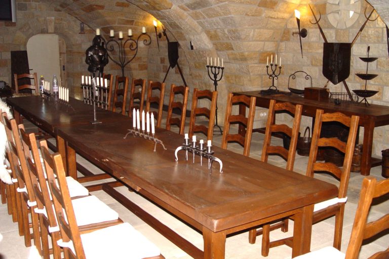 Partyraum Rittersaal - fürstlich feiern Langer Holztisch mit Stühlen in einem steinernen Weinkeller.