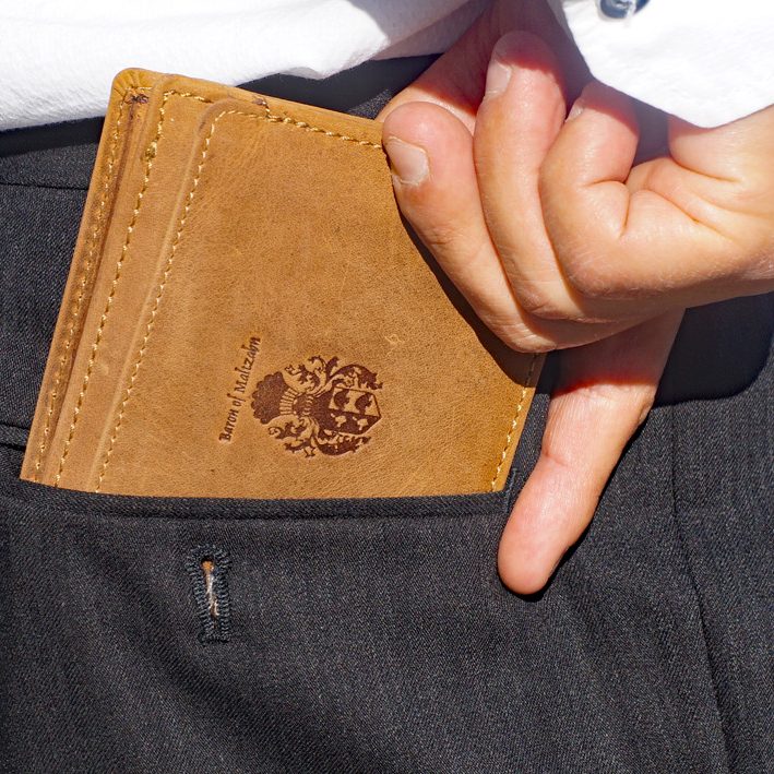 Ledertaschen Freiherr von Maltzahn Brauner Geldbeutel in einer Hosentasche, Hand greift hinein.